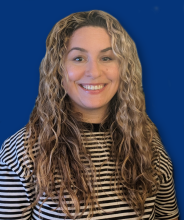 woman in black and white striped shirt smiling against blue background