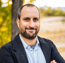 Man with facial hair standing outside smiling